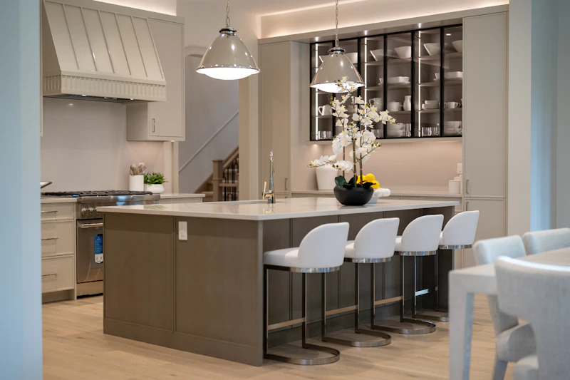 Kitchen with a gray island, quartz counters and white bar stools