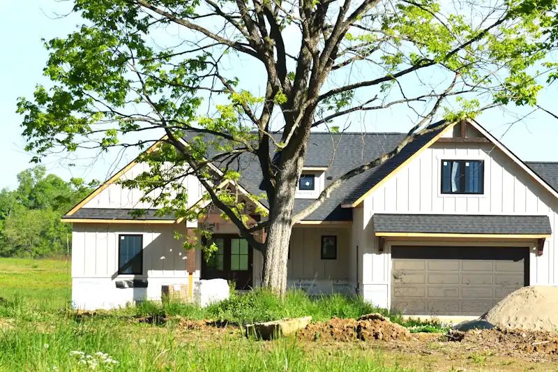 Newly built farmhouse with fresh grading and a dirt pile in the yard